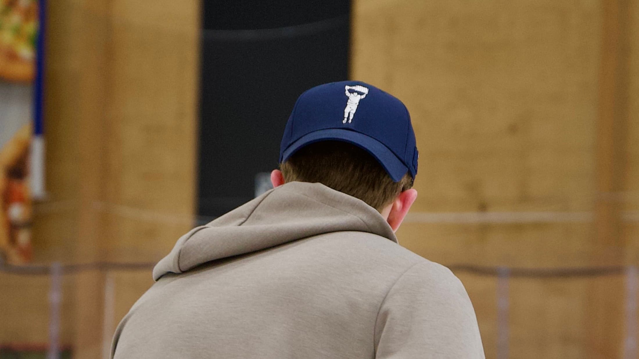IC3-grundare bakifrån i hoodie och Face-Off Cap inne i ishallen.